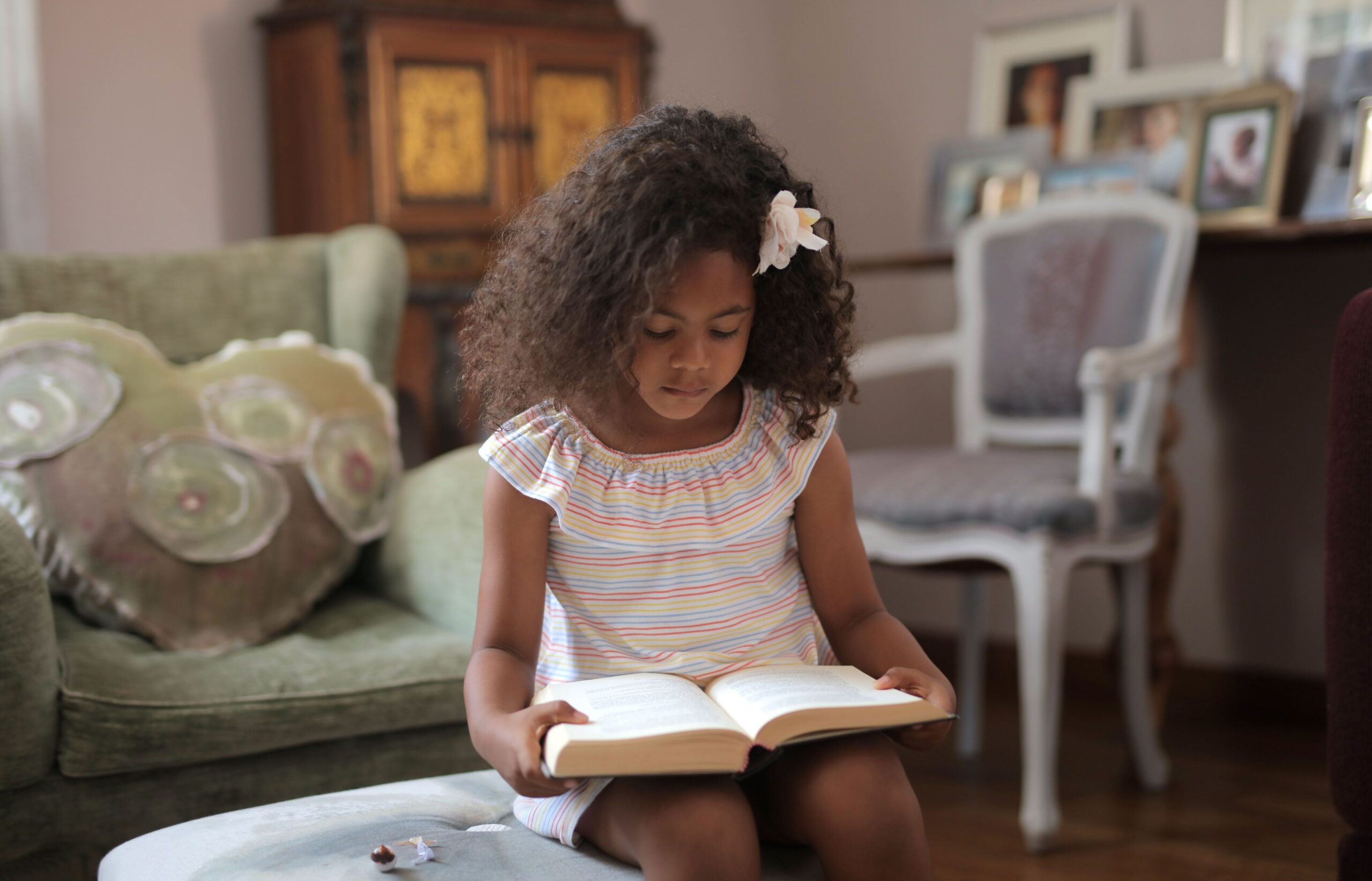 Criança lendo livro durante as férias escolares em ambiente aconchegante.