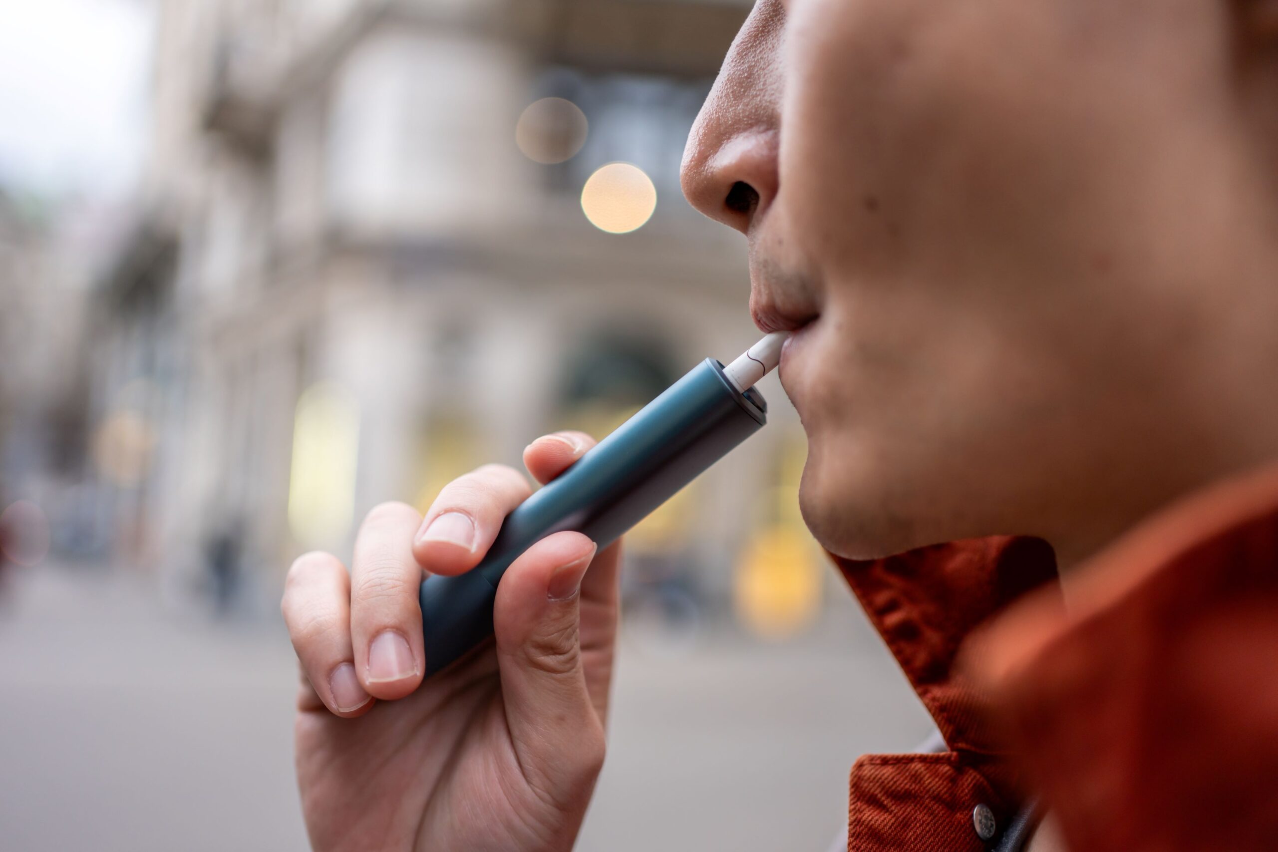 Jovem utilizando cigarro eletrônico, tema relacionado aos riscos de câncer de boca.